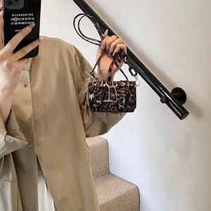 Detail of mini leopard print crossbody bag with black chain strap and metal lock clasp