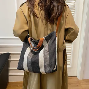 Gros plan détaillé d'un sac cabas en toile rayée avec des anses brunes porté sur un manteau