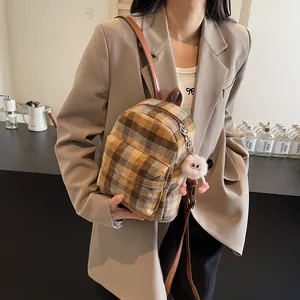 Detail of vintage plaid wool backpack with leather straps and plush charm in a cafe setting