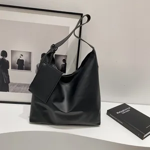 Detail of black large-capacity tote bag with knot strap and detachable coin pouch on white stand