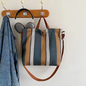 Gros plan du sac cabas en toile à rayures avec anses marron et bouton pression en métal