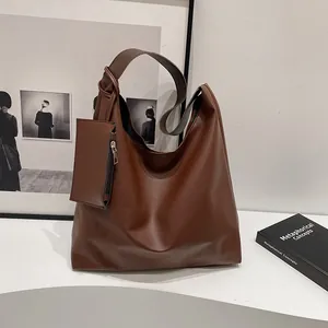 Detail of a dark brown hobo bag featuring a knotted strap and matching zipper pouch