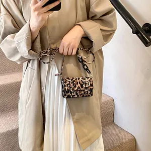 Close-up of leopard print mini crossbody bag with black acrylic chain and metal buckle