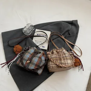 Detail of plaid wool bucket bags with drawstring closure and cute plush bear charm