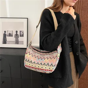 Dettaglio borsa a tracolla intrecciata colorata con cinturino in tessuto crema su modella