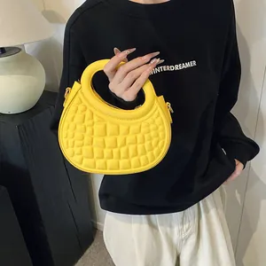 Detail of bright yellow crescent bag with quilted texture and gold metal buckle