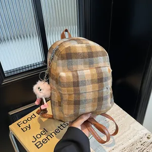 Detail of checkered woolen backpack with brown leather strap and pink plush toy