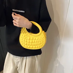 Detail of bright yellow semi-circle handbag with quilted texture and metal hardware