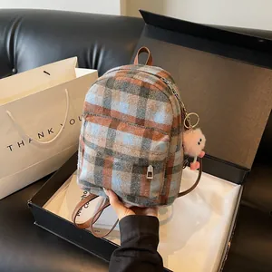Close-up of a plaid wool backpack in a gift box with a pink plush doll pendant