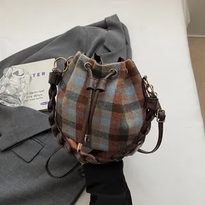 Detail of vintage plaid wool bucket bag with drawstring closure and leather straps