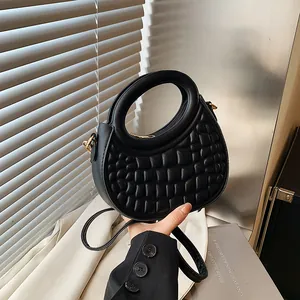 Detail of black crocodile pattern dumpling bag with circular handle and gold hardware