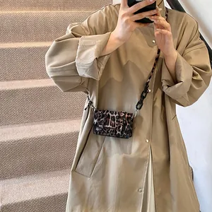 Detailed view of leopard print mini crossbody bag styled with a khaki trench coat