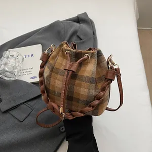 Detail of vintage brown plaid wool bucket bag with drawstring and woven handle