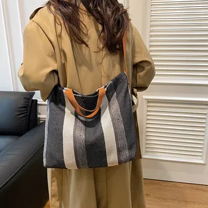 Grand sac cabas à rayures verticales et poignées contrastées porté par un mannequin femme