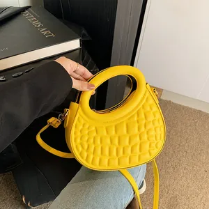Detailed view of yellow quilted puff shoulder bag with unique round handle and metal zipper