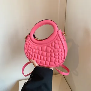 Detail of hot pink crossbody bag with unique pebble quilted texture and golden hardware