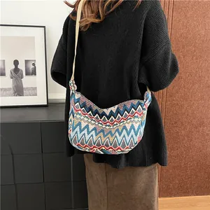 Dettaglio borsa a tracolla in tela intrecciata colorata con motivi etnici e tracolla bianca