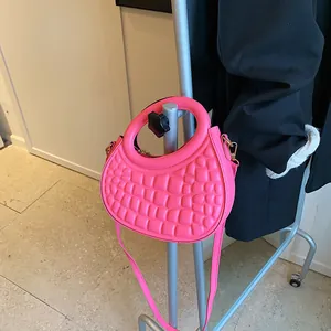 Detail of bright pink crescent bag featuring embossed bubble texture and a round handle