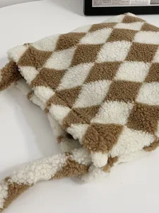 Close-up van de zachte pluche lamswol textuur en het bruine ruitjespatroon op de tas