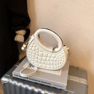 Detail of white quilted crescent bag with gold hardware and removable shoulder strap