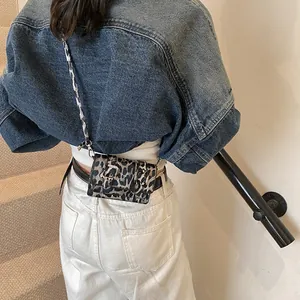 Detailed view of leopard print mini crossbody bag used as a stylish waist pack on belt
