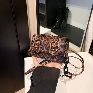 Close-up of leopard print mini crossbody bag with metal chain and buckle detail
