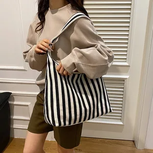 Sac cabas en toile à rayures verticales noires et blanches porté par un mannequin