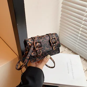 Detail view of mini leopard print crossbody bag with dual buckles and slim strap
