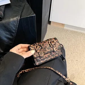 Detailed macro view of small leopard print crossbody bag with double buckle closure