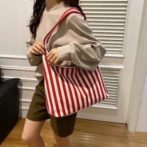 Détail d'un grand sac cabas en toile rayé rouge et blanc avec une large bandoulière confortable