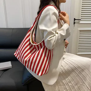 Détail d'un grand cabas en toile à rayures verticales rouges et blanches avec tenue décontractée