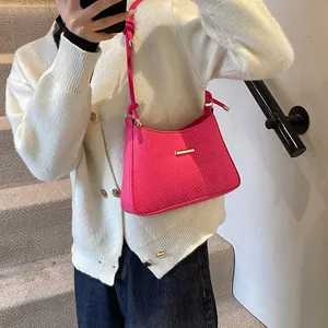 Detail of fuchsia shoulder bag with woven texture and gold metal knot strap accents