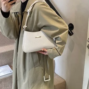 Detail of white woven textured shoulder bag with rope strap on a trench coat