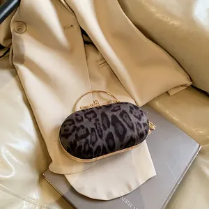 Dettaglio borsa da sera leopardata con manico dorato e tracolla su una giacca