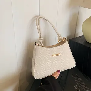 Detail of woven texture on cream shoulder bag with gold hardware and knotted handles