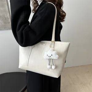 Detail of cream white tote bag featuring bark texture and cute plush cloud pendant