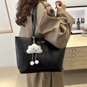 Detailed side view of black textured tote bag with cute cloud charm on model
