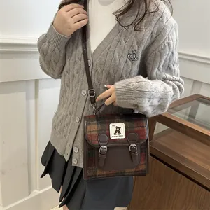 Dettaglio borsa a tracolla scozzese vintage con cinturini in pelle e patch orso