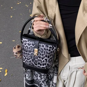 Close-up of leopard print bucket bag with black leather handle and golden twist lock detail