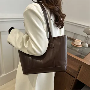Detail of dark brown tote bag with vertical wave texture shown on a white blazer