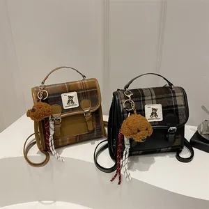 Dettaglio ravvicinato della trama scozzese vintage e cuciture in pelle di due borse a tracolla