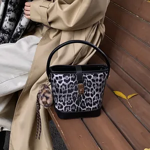 Detail der Bucket Bag mit Leopardenmuster, Ledergriff und goldenem Schloss auf einer Bank
