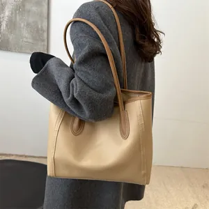 Dettaglio della borsa tote beige minimalista con manici marroni e cuciture a contrasto