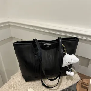 Detail of black tote bag with vertical texture and white cloud plush charm