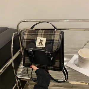 Dettaglio borsa in lana scozzese con patch a forma di orso e rifiniture in pelle