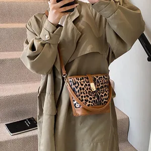 Chic leopard print bucket bag with brown leather trim shown on model with trench coat