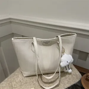 Detail of cream tote bag with herringbone texture and cloud plush charm