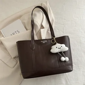 Detailed texture of dark brown tote bag with leather logo and cloud charm