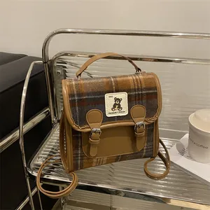 Dettaglio della borsa a mano in lana a quadri retrò con cinturini in pelle e patch orso
