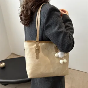 Detailed view of apricot suede tote bag with plush charm and side brand lettering